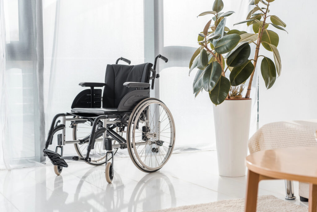 Wheelchair in front of a doorway, next to a plant. 