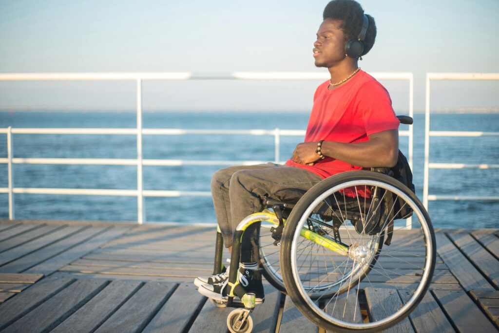 Man sitting in wheelchair by a beach dock.